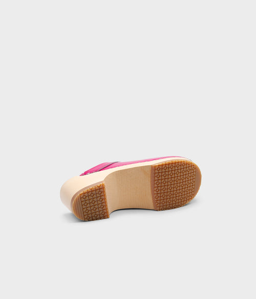 Pink shoe with a brown sole on a light gray background