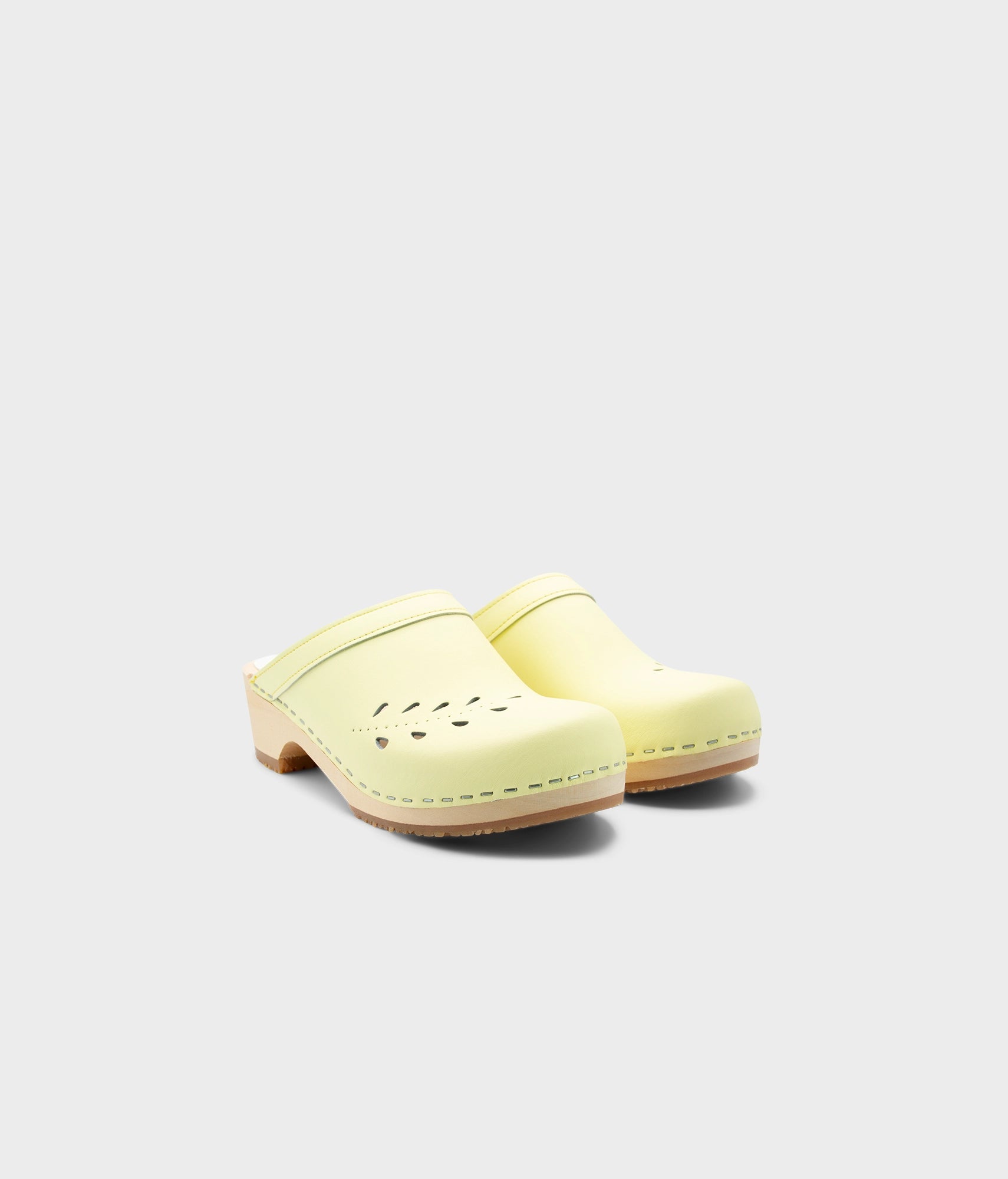 Pair of light yellow clogs on a white background