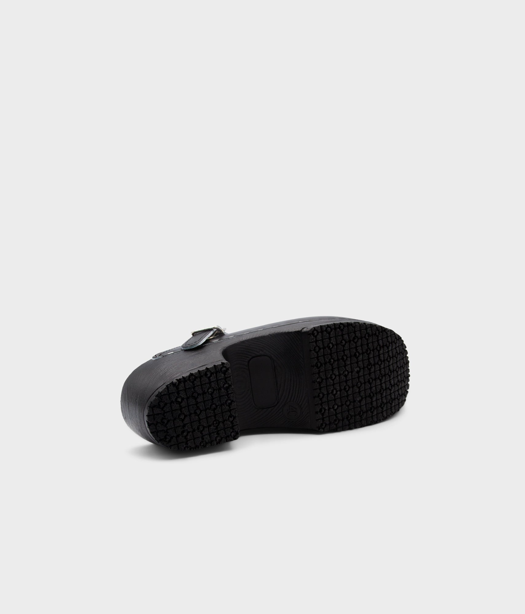 Black rubber sole of a shoe on a light gray background