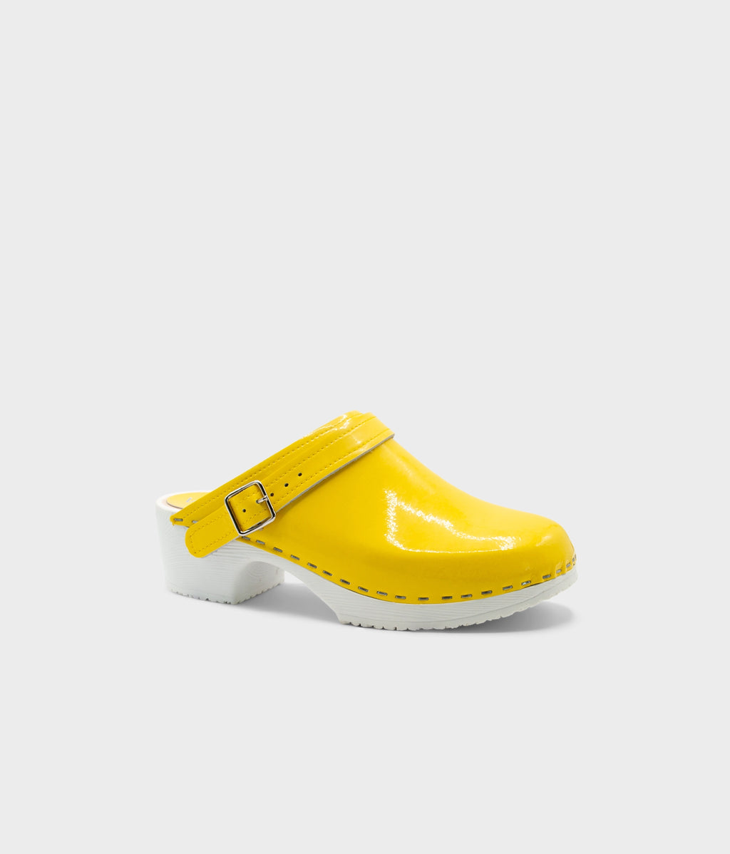 Yellow clog shoe with a white sole on a light gray background