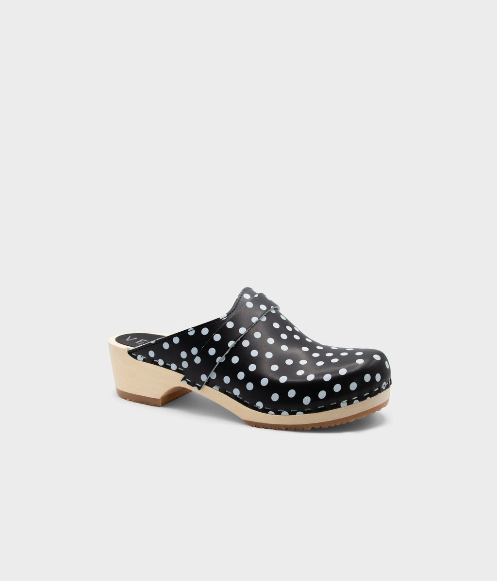 Black clog shoe with white polka dots on a light gray background