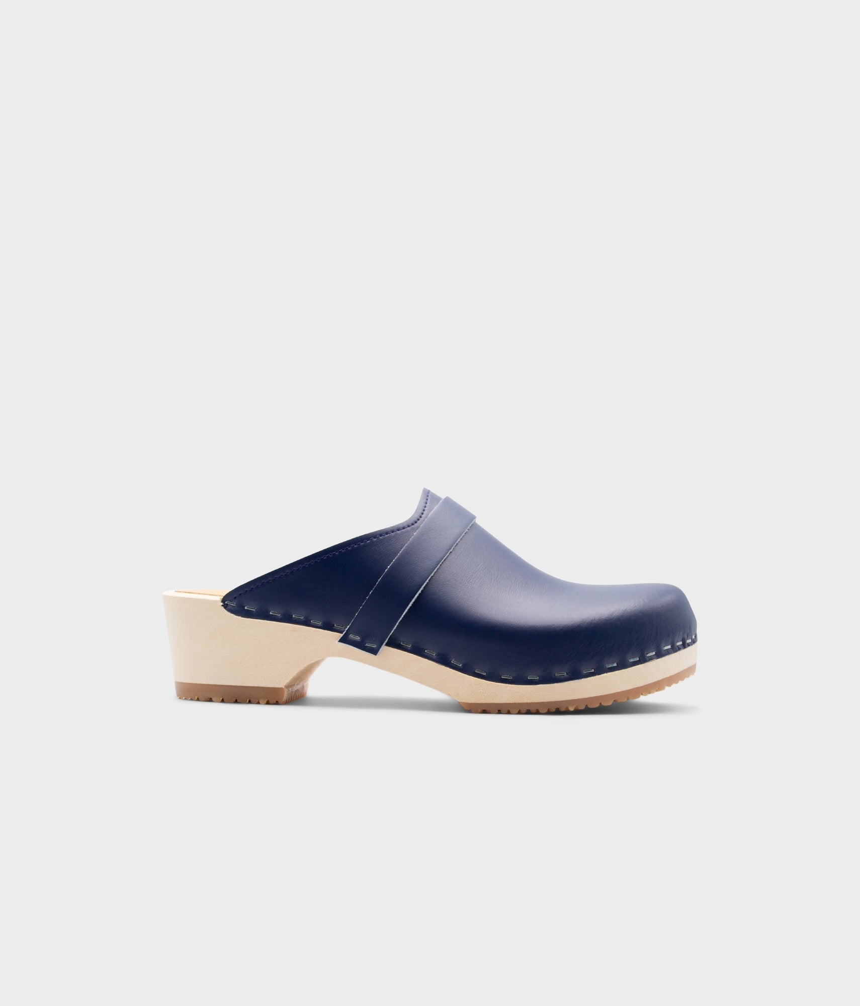 Navy blue clog shoe with a beige sole on a light gray background