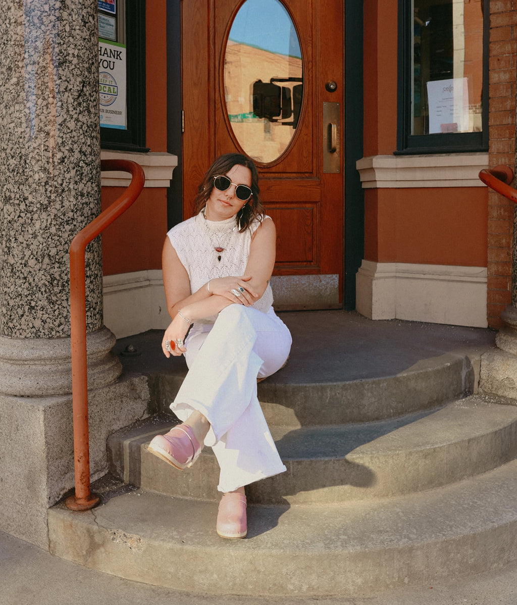 Woman sitting on steps in front of a building entrance