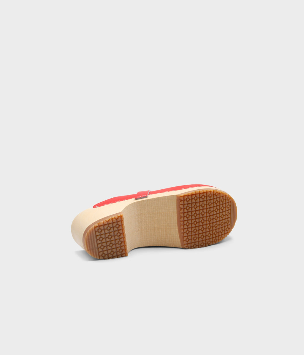 Red shoe with a brown sole on a light gray background