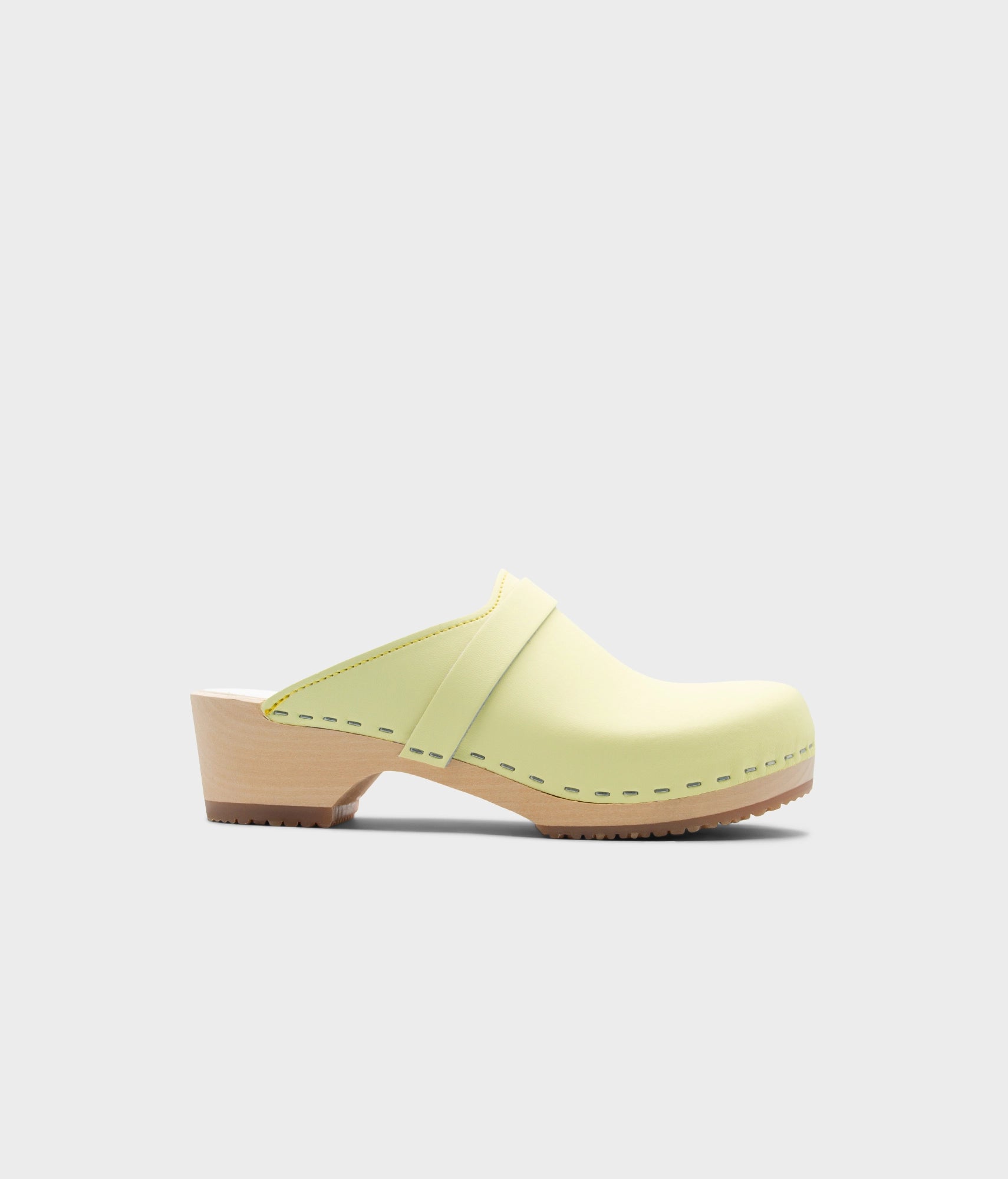 Light yellow clog mules on a white background