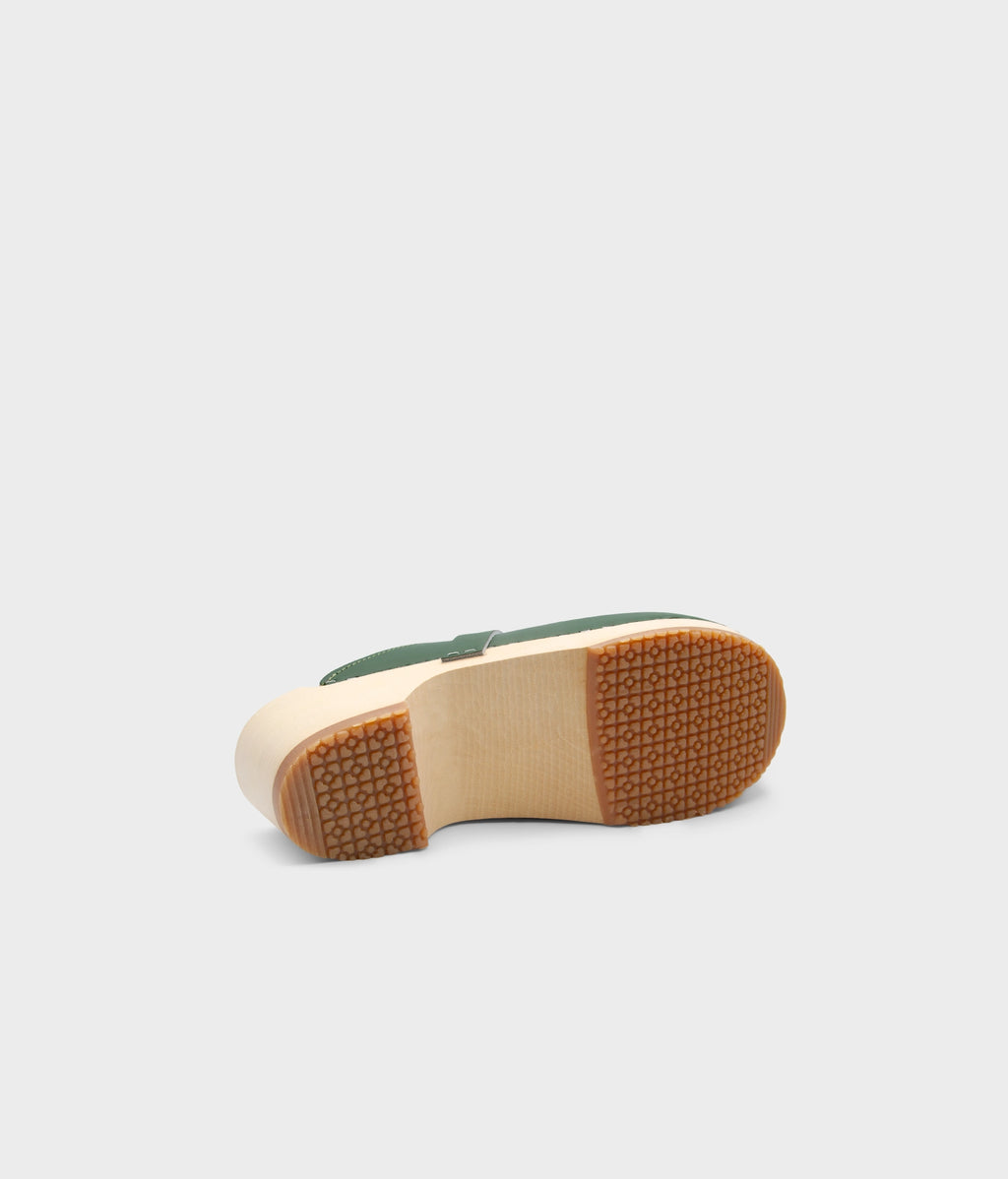 Green clog mule sole with brown rubber sole on a light gray background