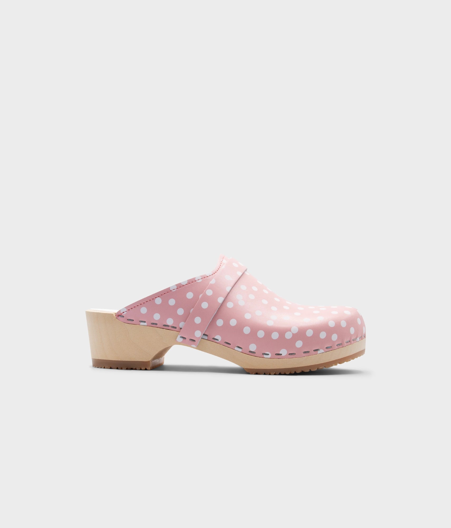Pink clog shoe with white polka dots on a light gray background