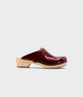 Single cherry colored clog shoe on a light gray background