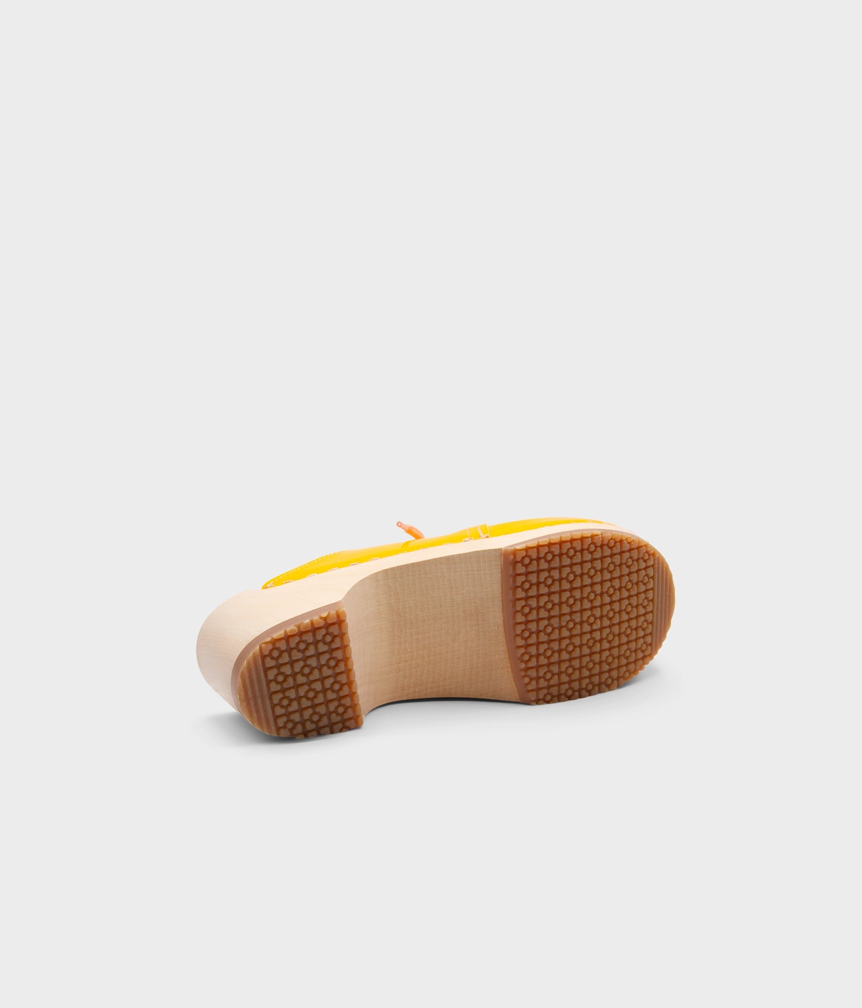 Yellow shoe sole with brown sole on a light gray background