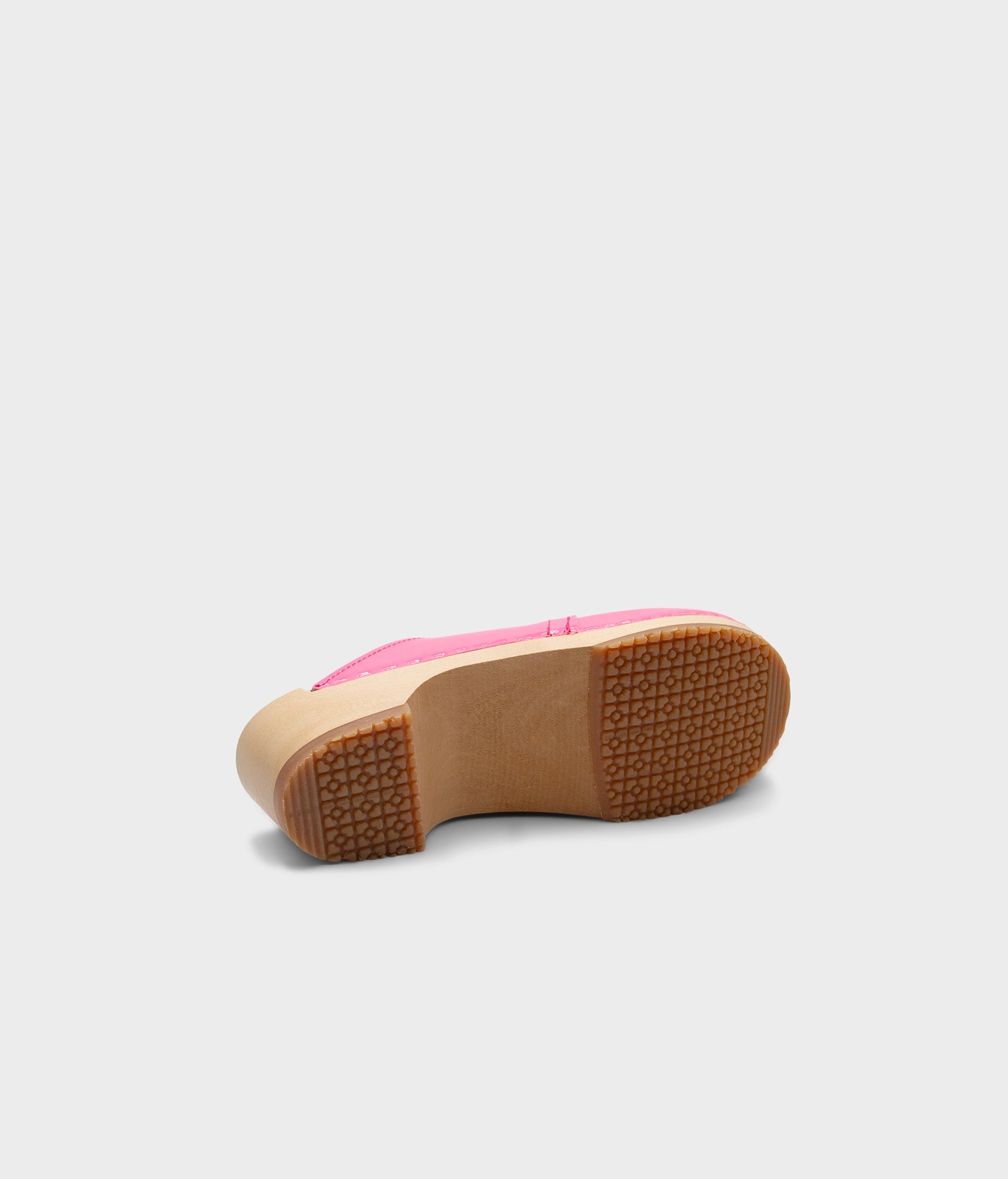 Pink shoe sole with brown sole on a light gray background