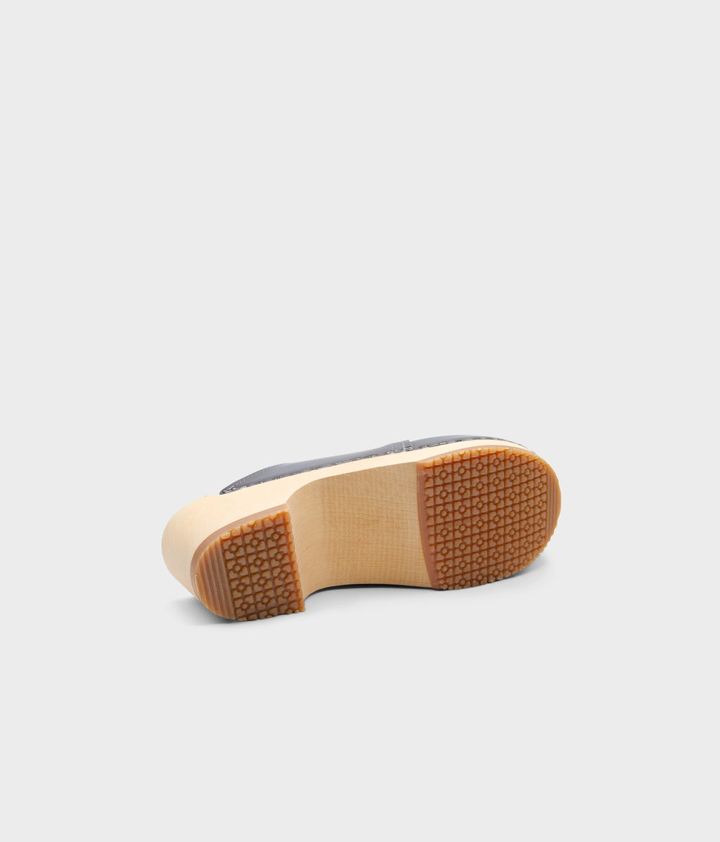 Close-up of a shoe sole with a textured brown rubber outsole on a light gray background