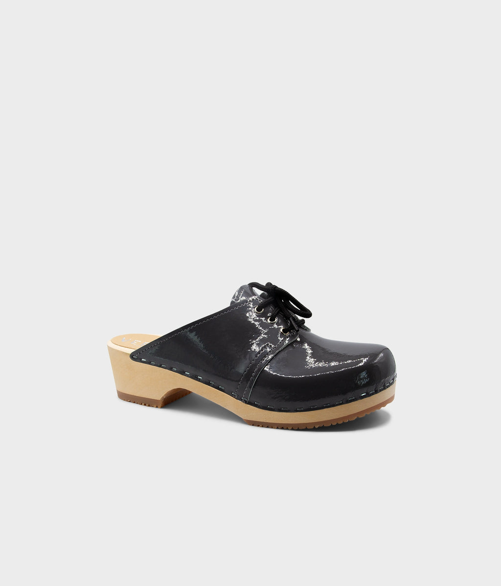 Black clog shoe with a wooden sole on a light gray background