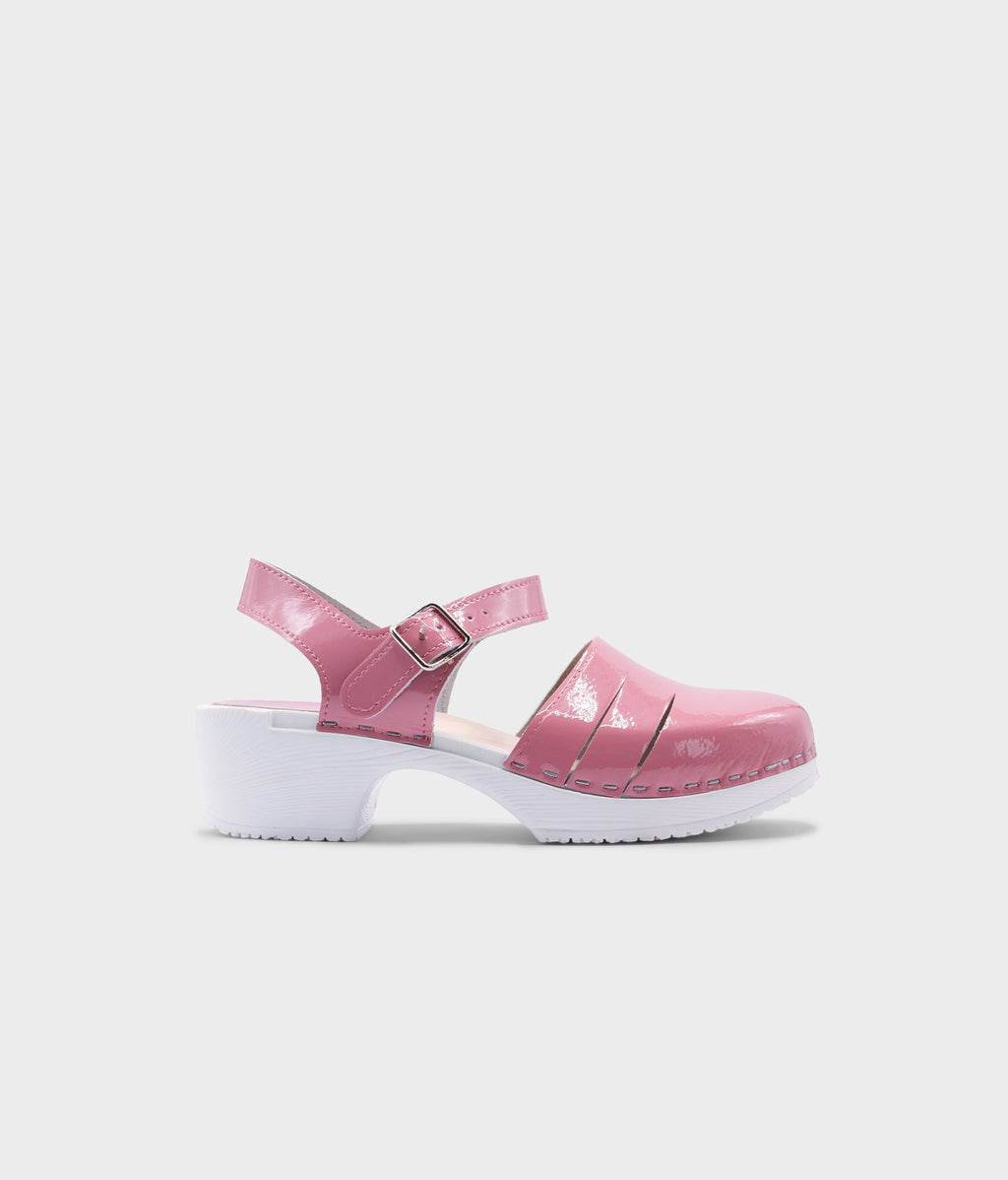 A single pink patent leather clog sandal with a white platform sole, shown in profile against a light gray background.