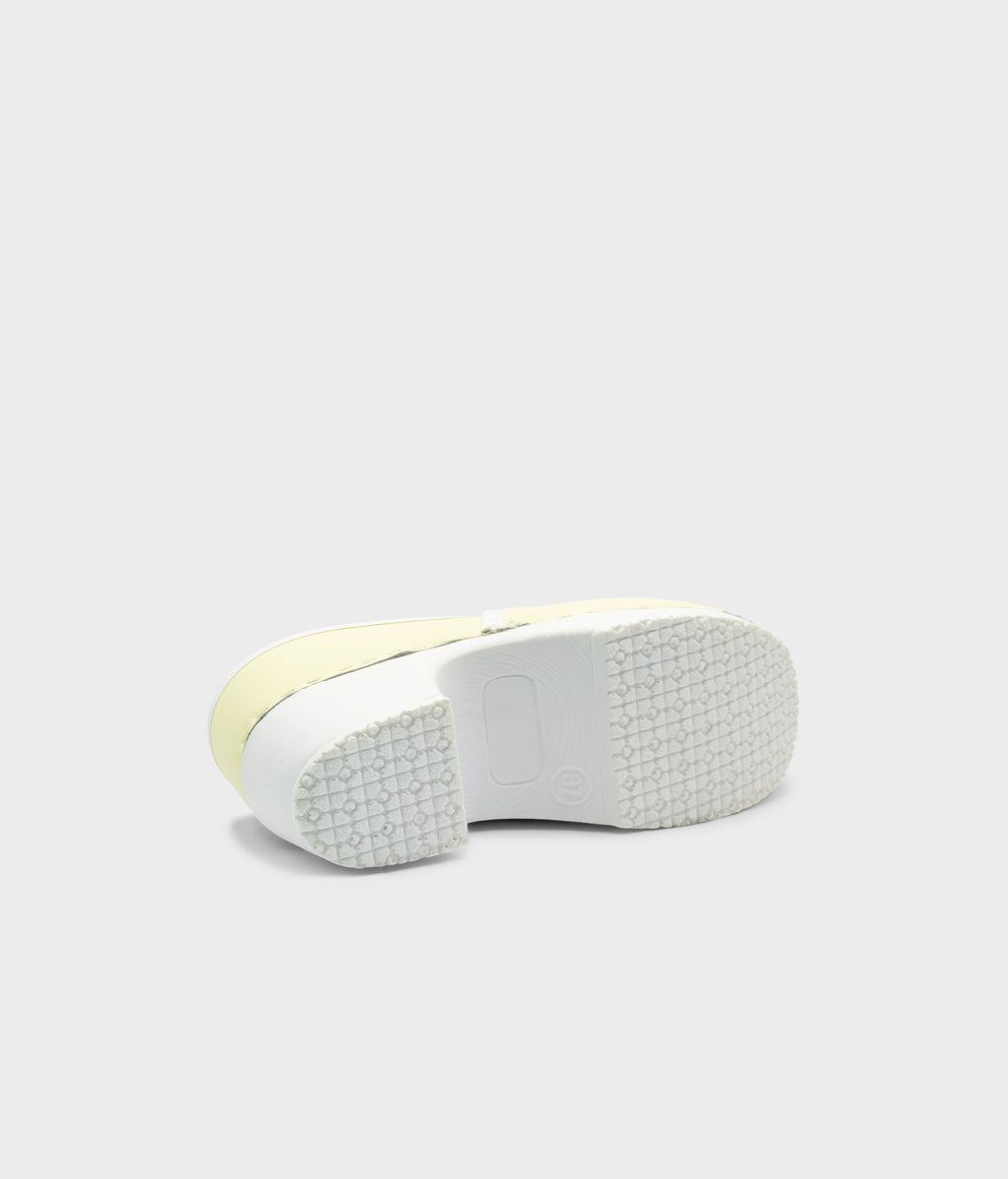Close-up of a shoe sole with a white sole and yellow edge on a light gray background