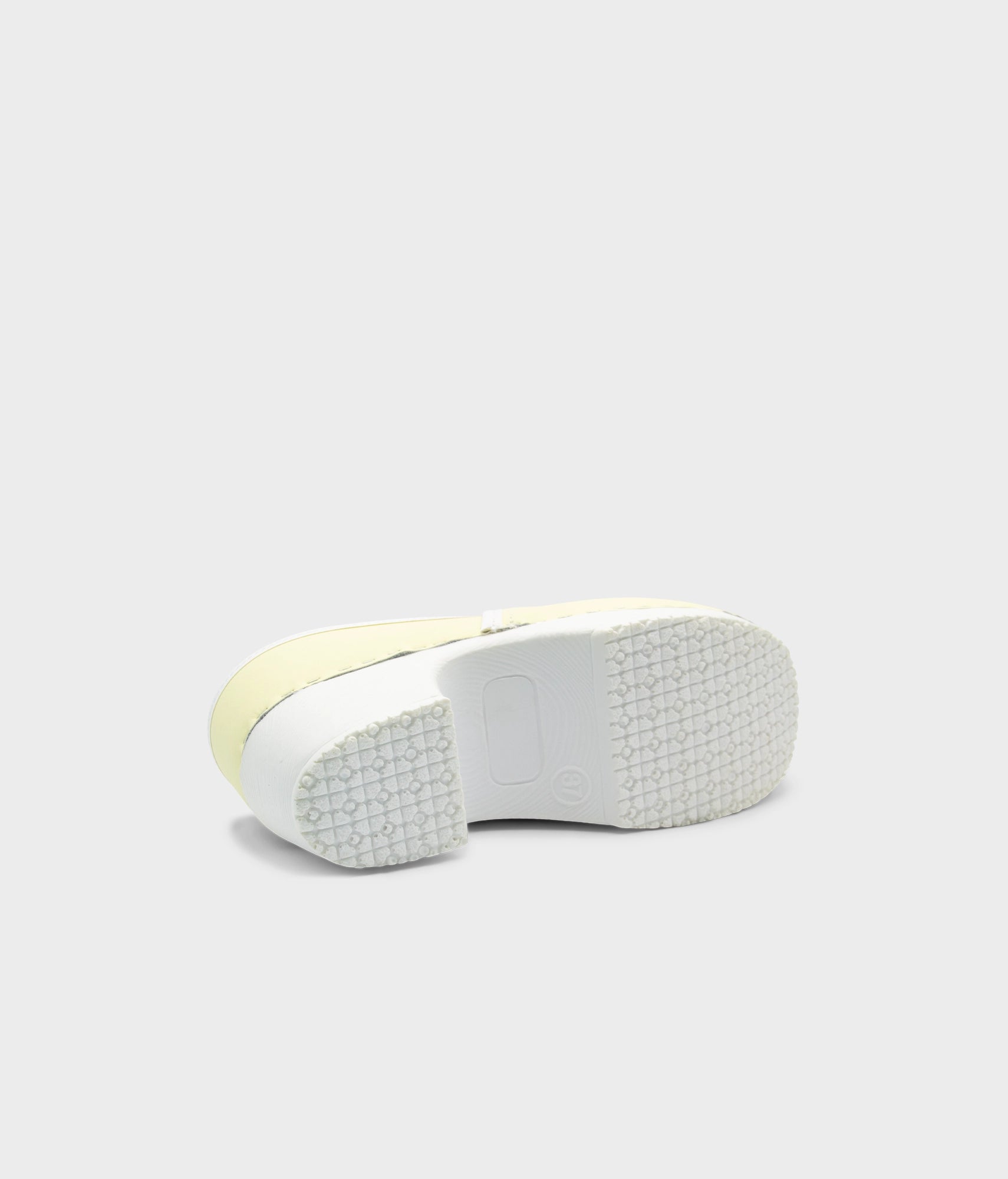 Close-up of a shoe sole with a white sole and yellow edge on a light gray background
