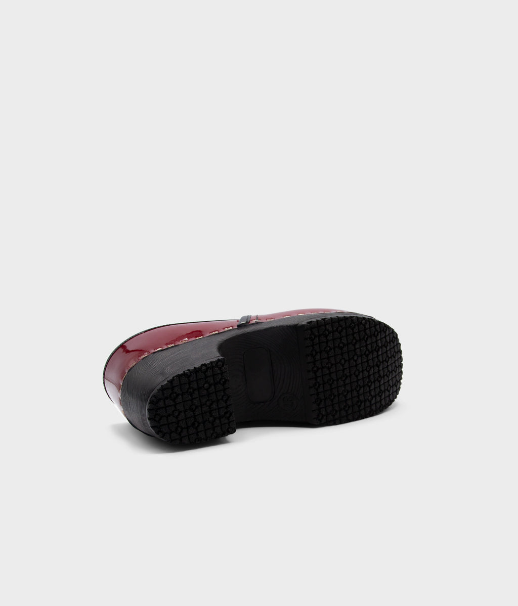 Red slip-on shoe with black sole on a light gray background