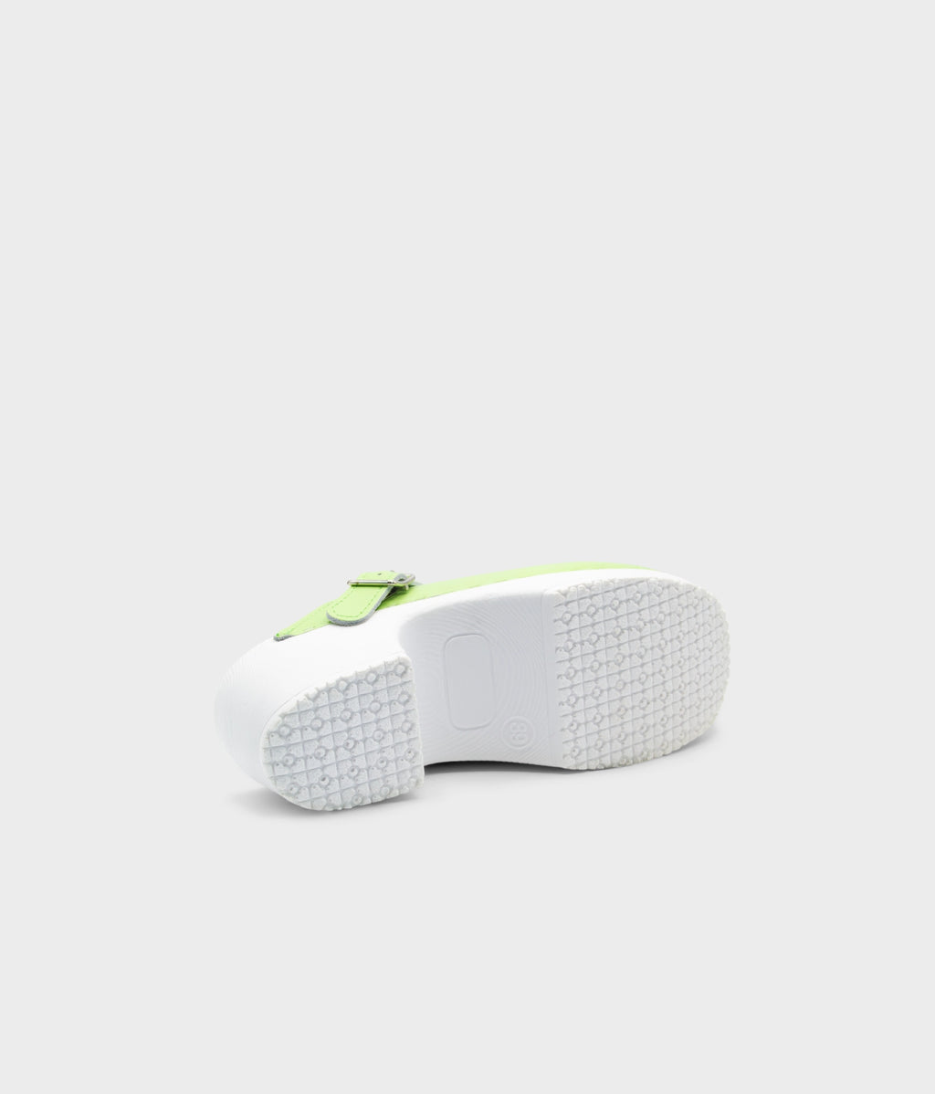 White sneaker with a green sole on a light gray background