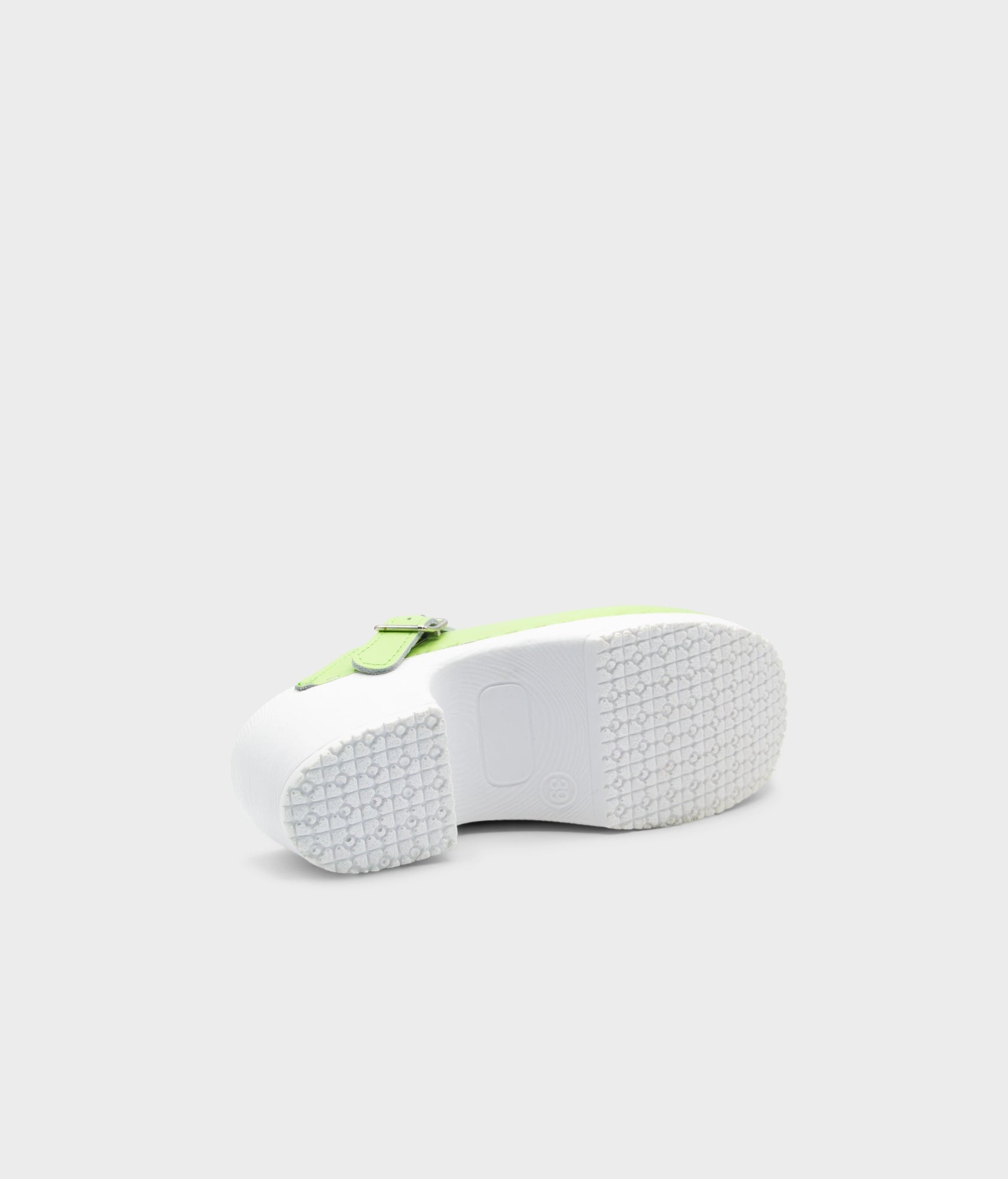 White sneaker with a green sole on a light gray background