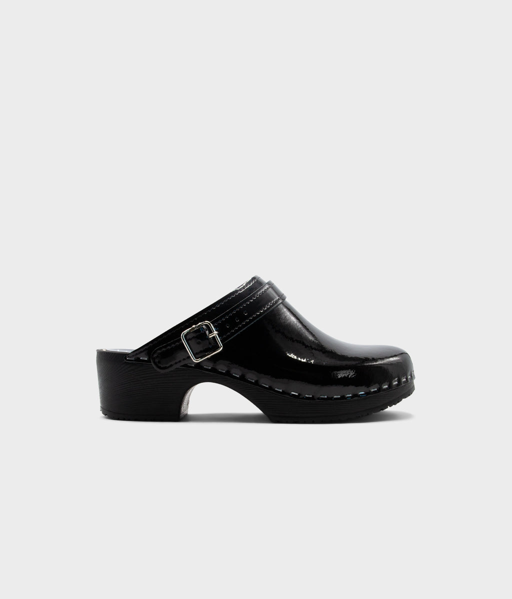 Black clog shoe with a strap on a light gray background