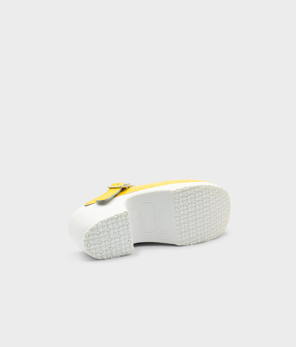 White sandal with yellow strap on a light gray background