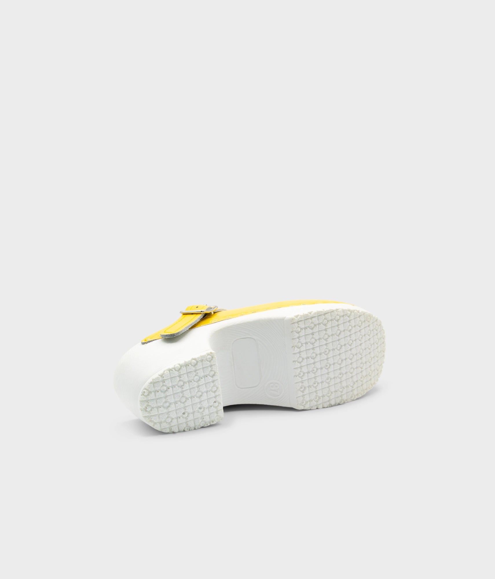 White sandal with yellow strap on a light gray background