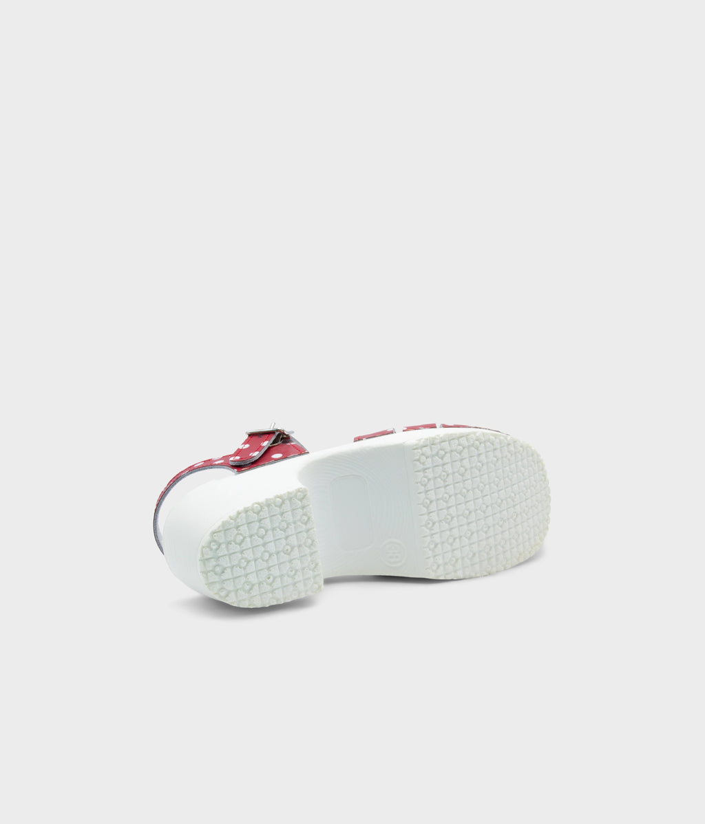 White shoe with a red sole on a light gray background